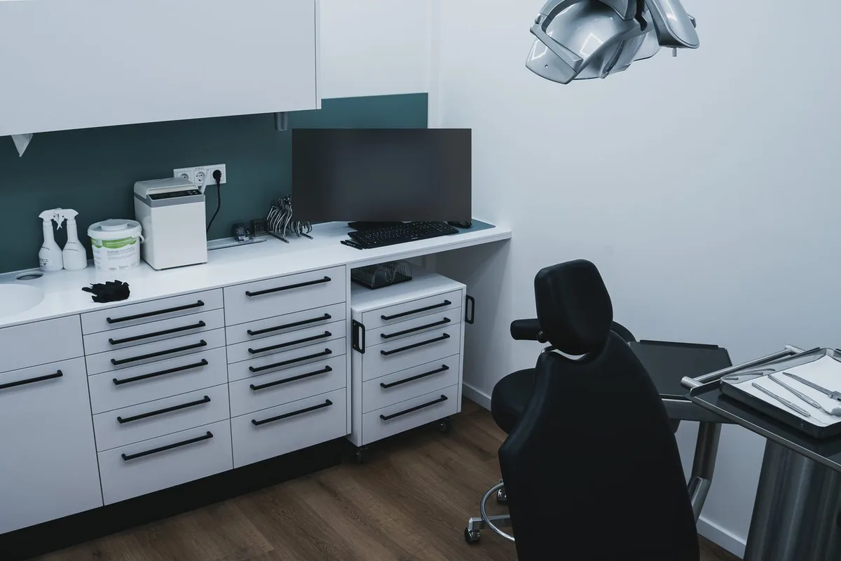 Behandlungszimmer der Praxis mit Behandlungsstuhl, Instrumentenablage und Einbauschränken