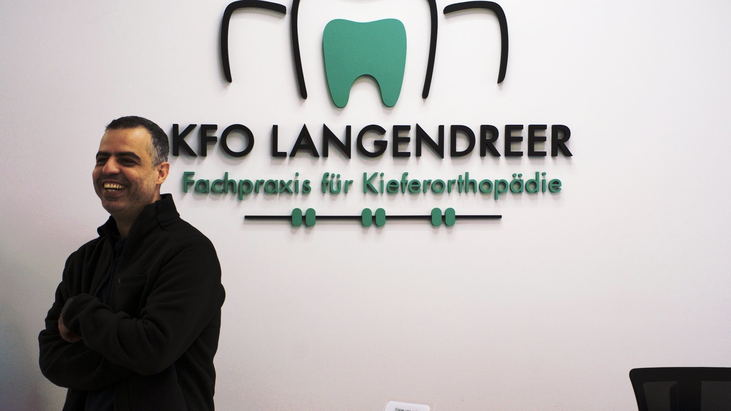 Ahmed Abudayya M.Sc. vor dem Praxisschild von KFO Langendreer