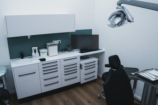Behandlungszimmer mit Einbauschränken, Behandlungsstuhl und Deckenleuchte